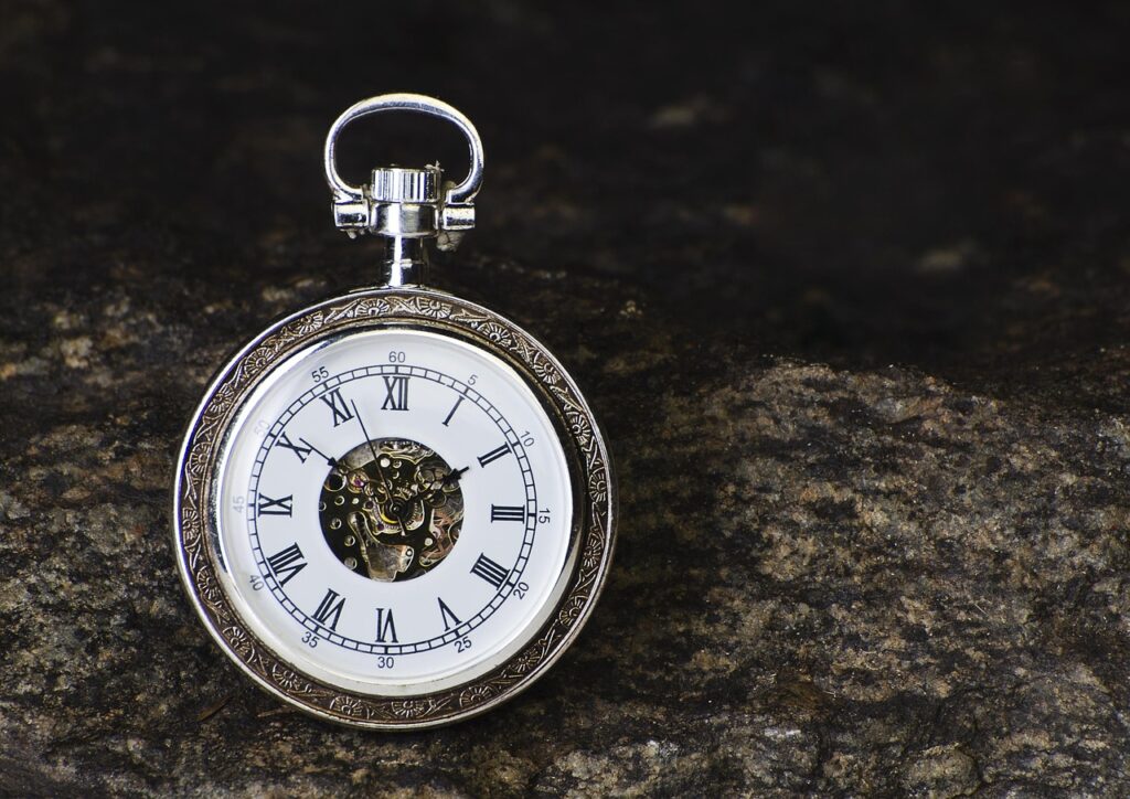 Een zilverkleurig zakhorloge met een witte wijzerplaat.