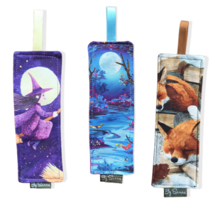 Drie verschillende boekenhoezen als voorbeeld. Een met een heks, een met een volle maan en vlinders en een met een slapend vosje.