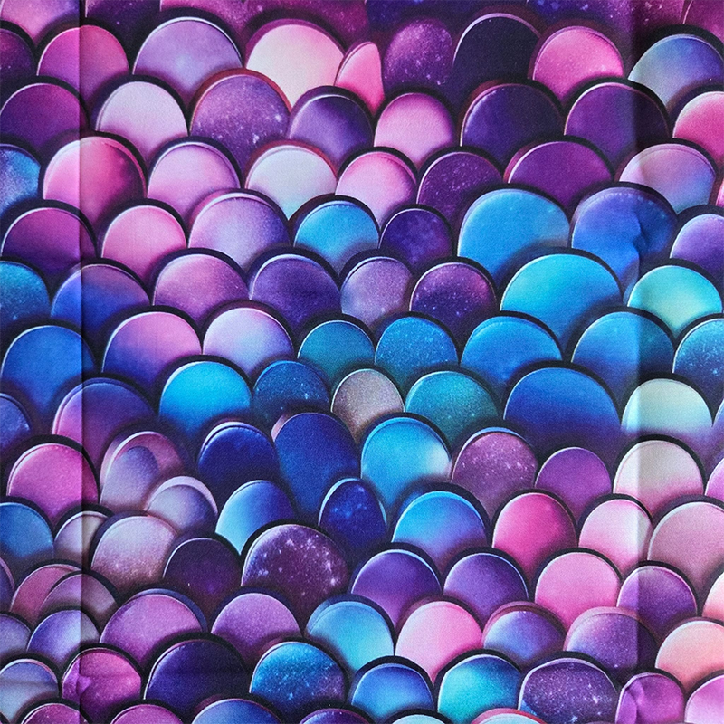 Deze katoenen stof heeft een patroon van drakenschubben in de tinten roze, blauw en paars.